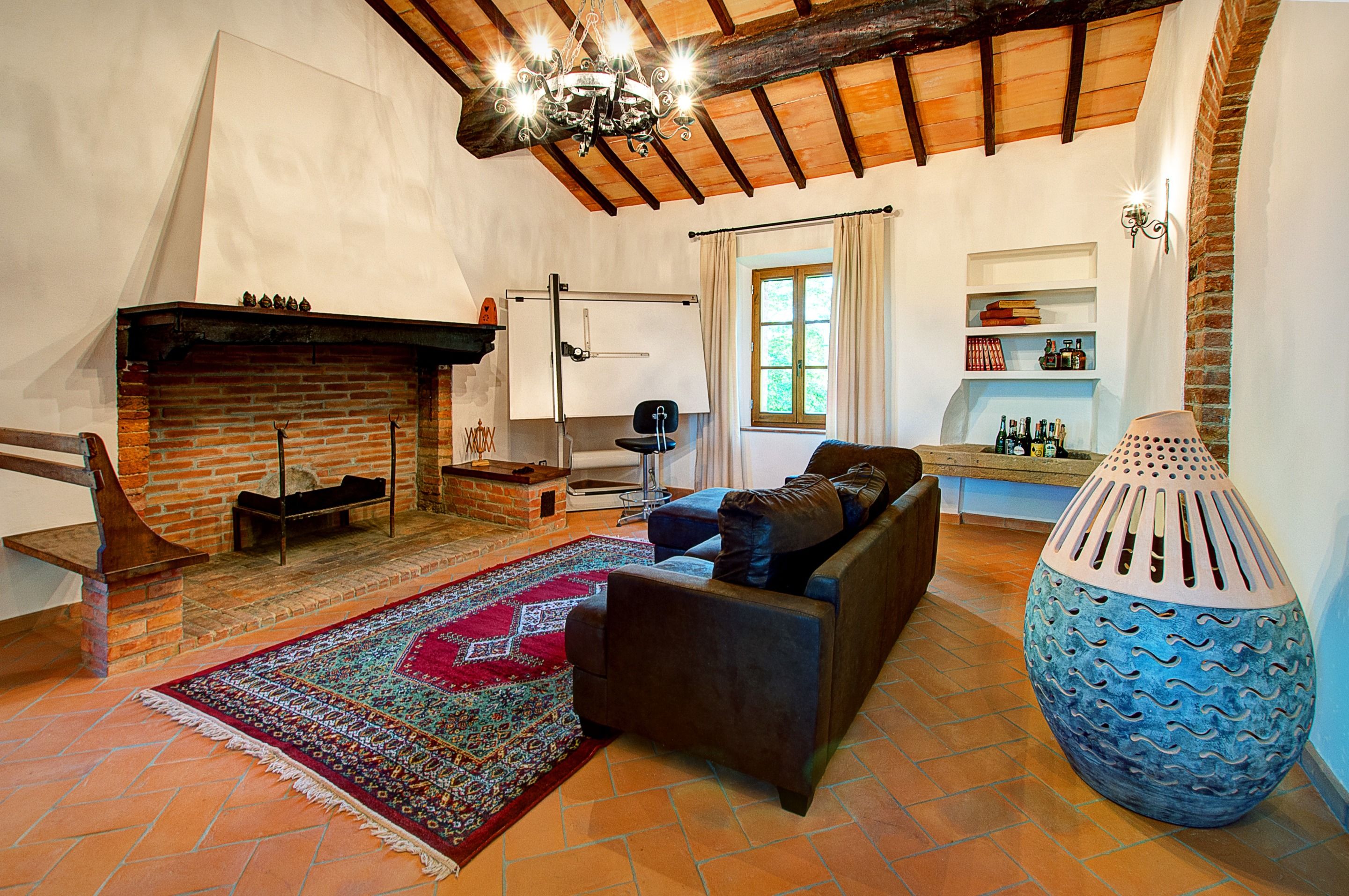 A cozy living room with a fireplace, a sofa, a patterned rug, and a large decorative vase.
