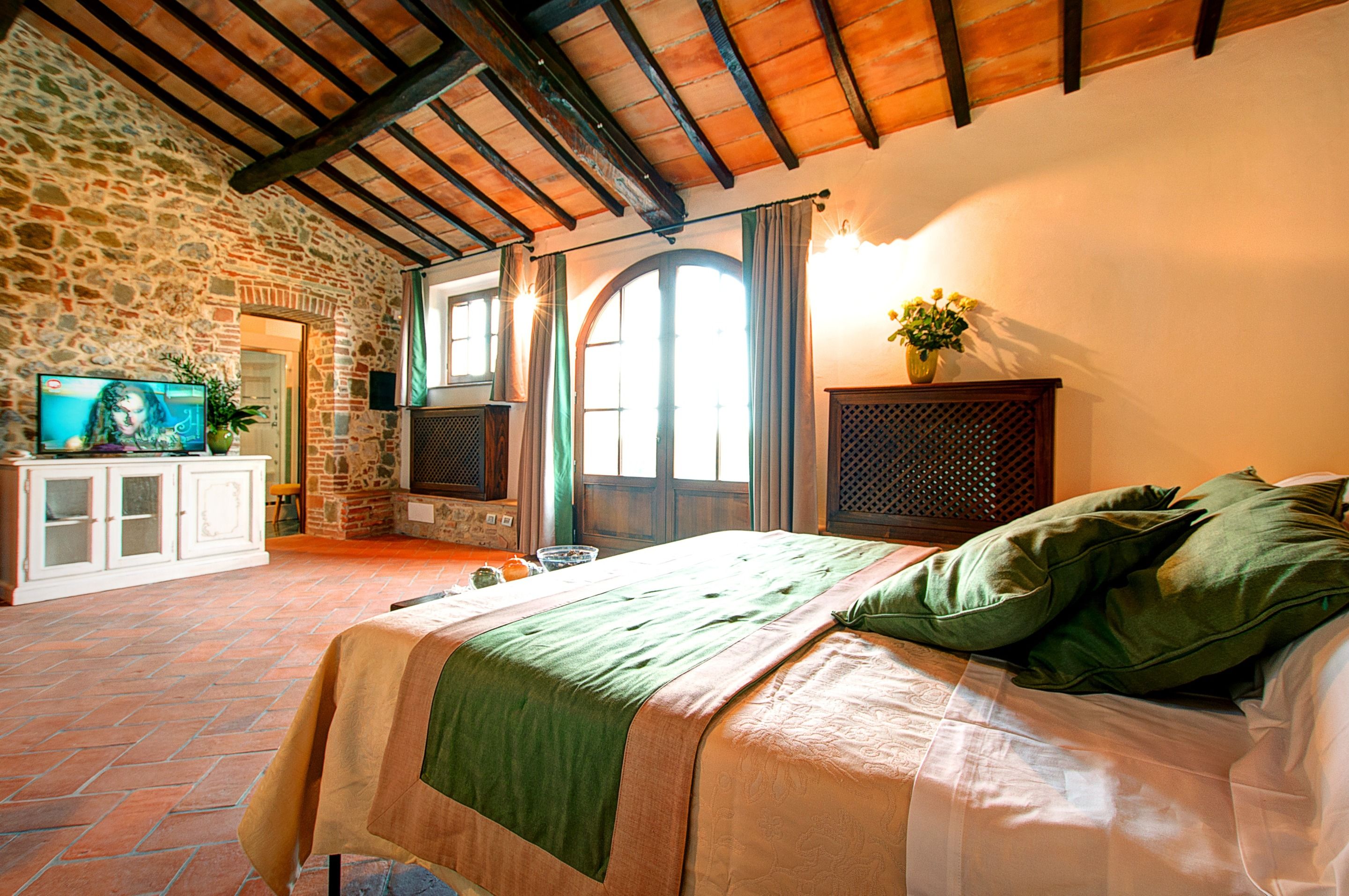 Ein Schlafzimmer mit einem Bett, einem Fernseher, einer Steinsäule und einem Fenster.