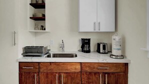 A kitchen with white cabinets, a stainless steel sink, a coffee maker, and a toaster. - 1 BR Studio w/ King Bed + Easy Beach Access (Nassau)