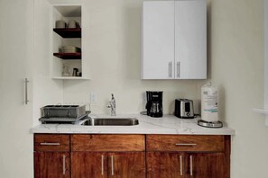 A kitchen with white cabinets, a stainless steel sink, a coffee maker, and a toaster. - 1 BR Studio w/ King Bed + Easy Beach Access (Nassau)