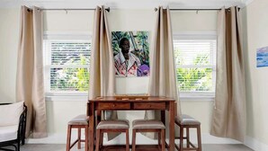 A room with a wooden desk, two chairs, a window with blinds, and a painting on the wall. - 1 BR Studio w/ King Bed + Easy Beach Access (Nassau)