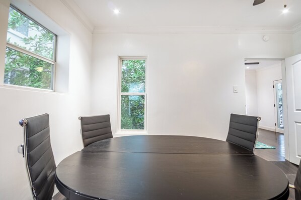 Une salle de conférence équipée d’une table ronde, de quatre chaises et de grandes fenêtres donnant sur un paysage verdoyant.