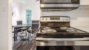 Une cuisine moderne équipée d’une cuisinière en acier inoxydable, d’un four à micro-ondes placé au-dessus, et d’un coin repas avec une table et des chaises.