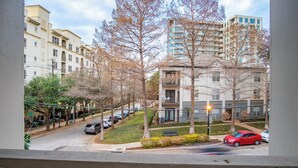 Une rue résidentielle bordée de voitures garées, d’arbres et d’immeubles à plusieurs étages.