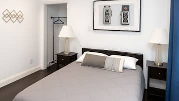 Une chambre d’hôtel avec un lit, deux tables de chevet avec des lampes, une armoire et un tableau encadré au mur.