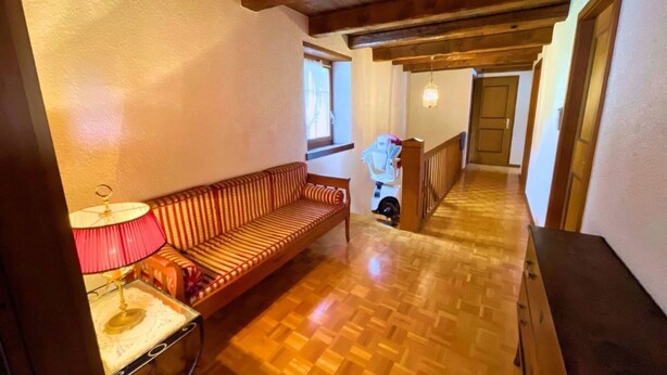 Een houten vloer, een bank, een lamp en een trap naar een andere kamer.