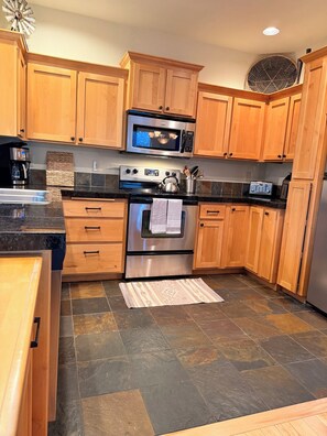 A kitchen with wooden cabinets, a stainless steel oven, a microwave, and a coffee maker.