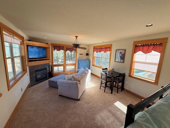 A living room with a fireplace, a sofa, a TV, and a dining area with a table and chairs.