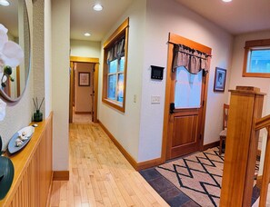 A hallway with wooden flooring, a wooden door with a checkered valance, and a window with a view. - The Hideout at Eagle Crest Resort with a Private Hot Tub and Walking Distance to Lakeside Sport Center Pool, multiple living spaces, kids nook, sleeps 7. (Redmond)