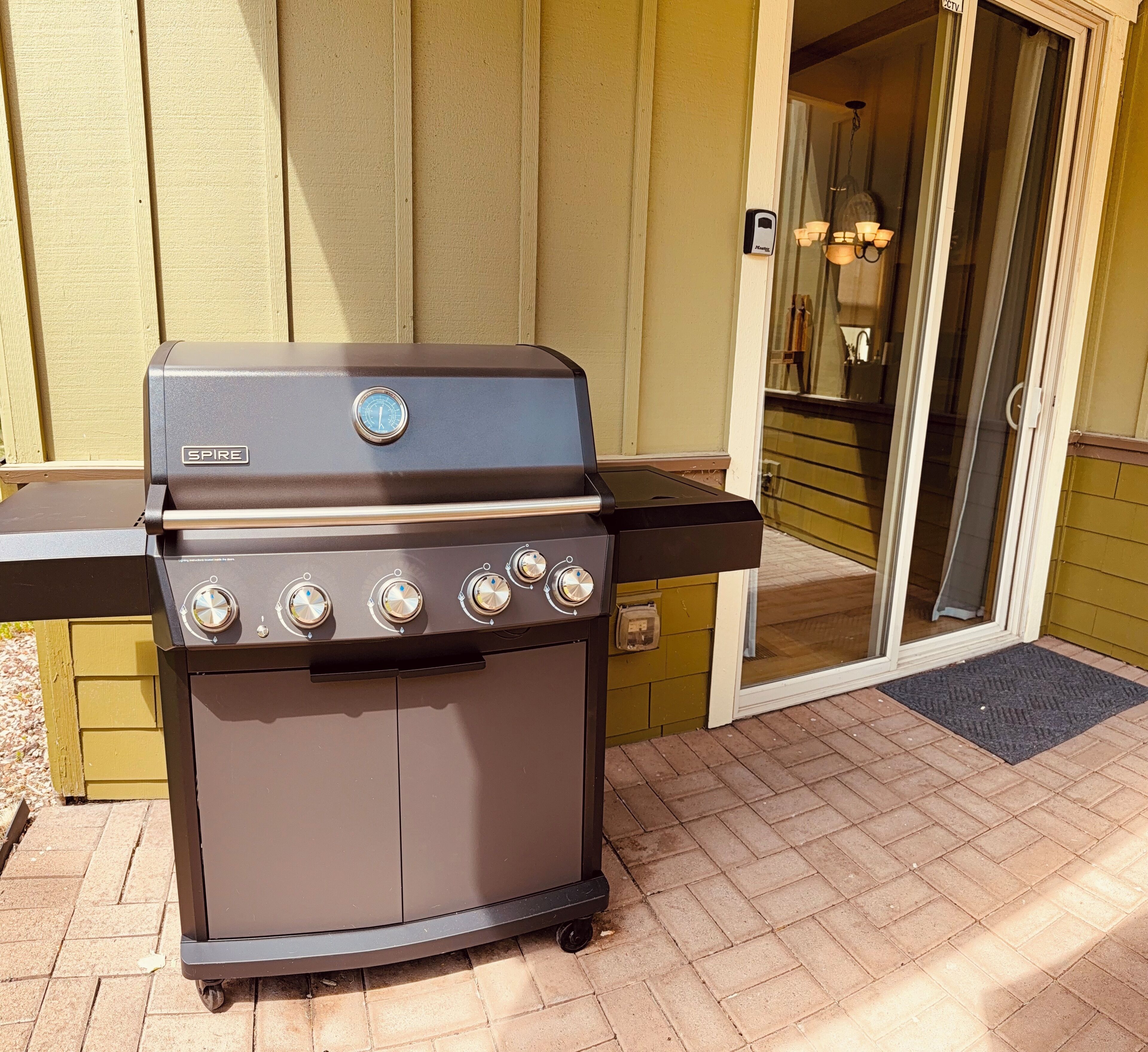 A SPIRE barbecue grill with four burners, a digital temperature gauge, and a side shelf.