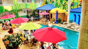 An indoor pool area with multiple umbrellas, seating, and a decorative mural.