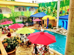 An indoor pool area with multiple umbrellas, seating, and a decorative mural.