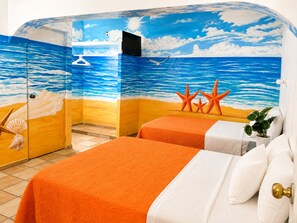A room with two beds, a beach-themed mural, and a small plant.
