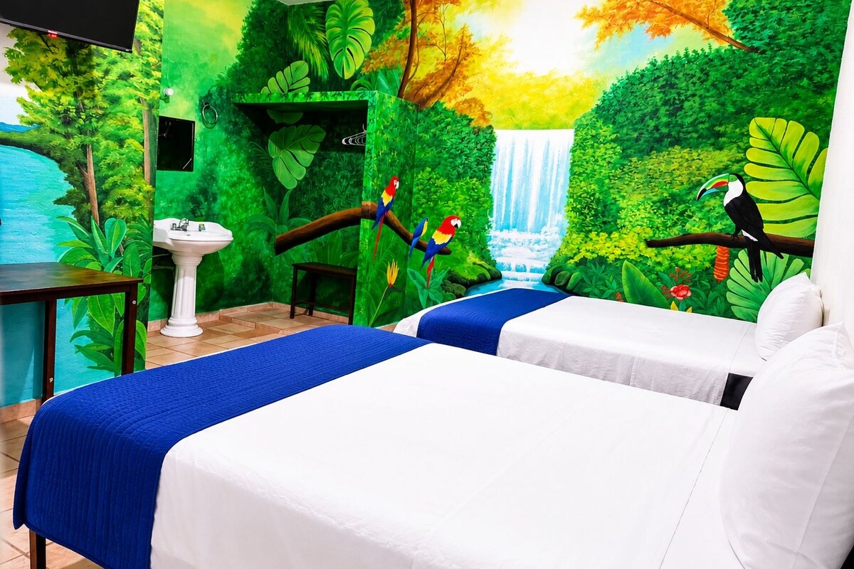 A room with two beds, a sink, and a mural of a waterfall and jungle.