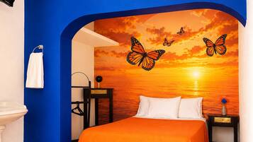 A bedroom with a bed, a nightstand, a wall-mounted shelf, and a bathroom with a sink and towel rack.