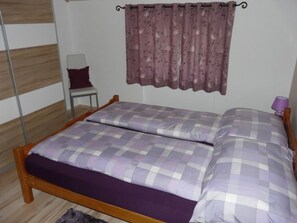 Une chambre à coucher avec un lit, une chaise, un rideau et une lampe.