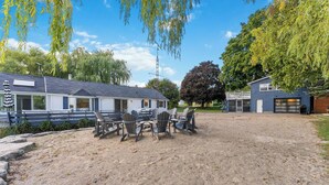 Een caravan met een omheind buitengebied, zitplaatsen buiten en een gebouw met een garage.