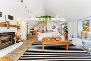 A spacious living room with a fireplace, a sofa, a coffee table, and a striped rug. - Private Waterfront Retreat! Sunny Lakehouse + 4 Cottages & 10 King Beds (Prince Edward)