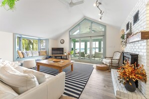 Ein großzügiges Wohnzimmer mit einem großen Fenster, einem Kamin und einem Fernseher.