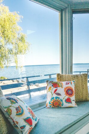 A view from a window with a bench and cushions, overlooking a body of water. - Private Waterfront Retreat! Sunny Lakehouse + 4 Cottages & 10 King Beds (Prince Edward)