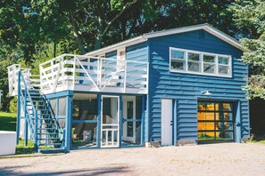 Ett tvåvåningshus med blå fasad, en veranda och ett garage.