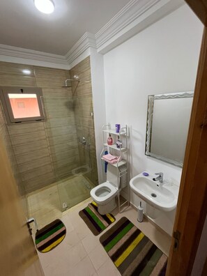 Ein Badezimmer mit Dusche, Toilette, Waschbecken und Spiegel.