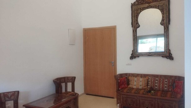 A room with a wooden door, a wooden bench, a sofa with patterned cushions, and a large ornate mirror on the wall. - Charming Duplex in enchanting Marrakesh with cool AC (Marrakesh)