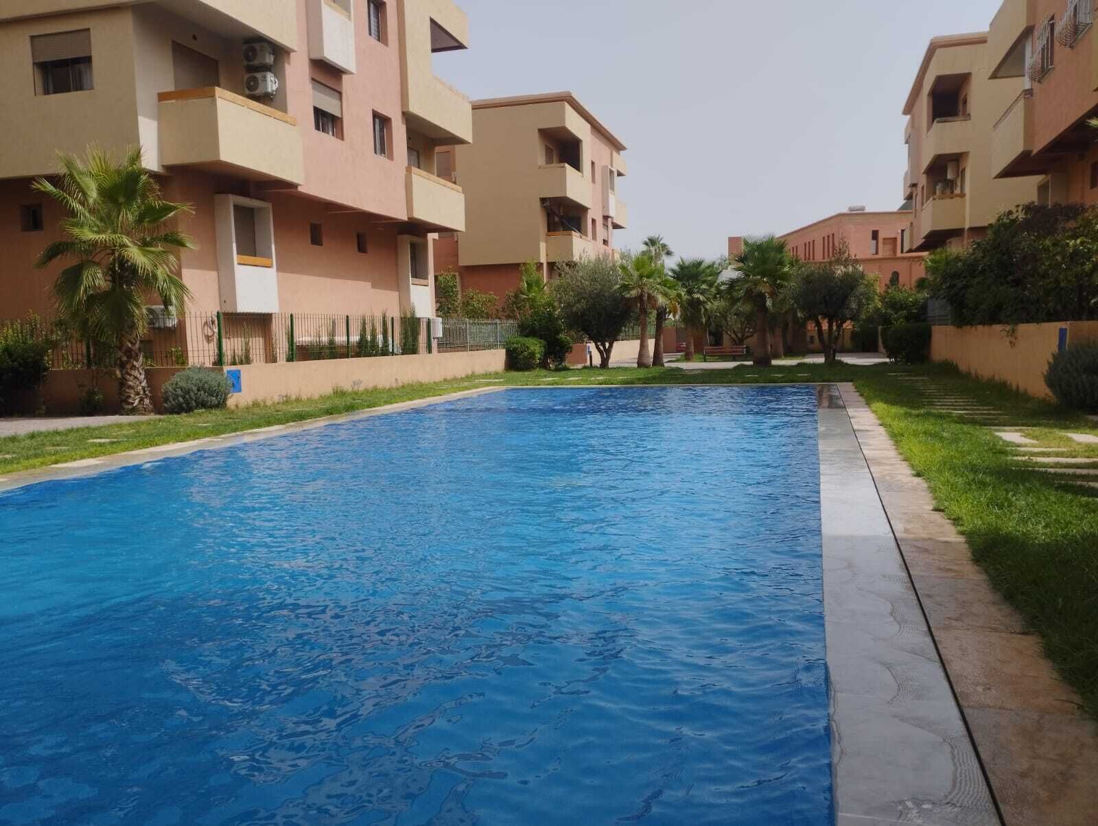 A swimming pool surrounded by apartment buildings with balconies.