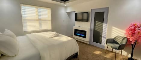 Une chambre à coucher avec un lit, une télévision, une cheminée et une fenêtre avec des stores.