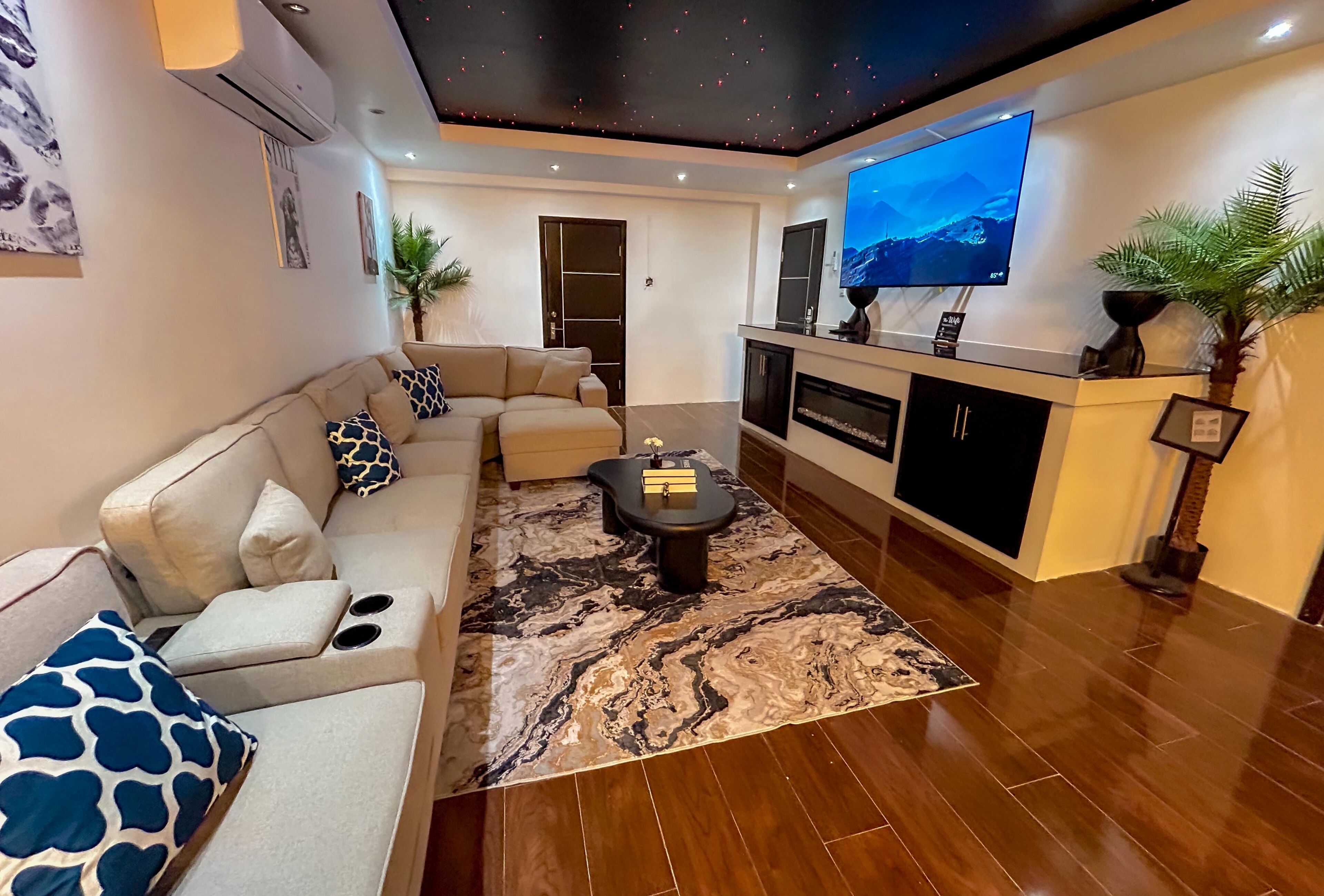 A modern living room with a sofa, coffee table, and a flat-screen TV mounted on the wall.
