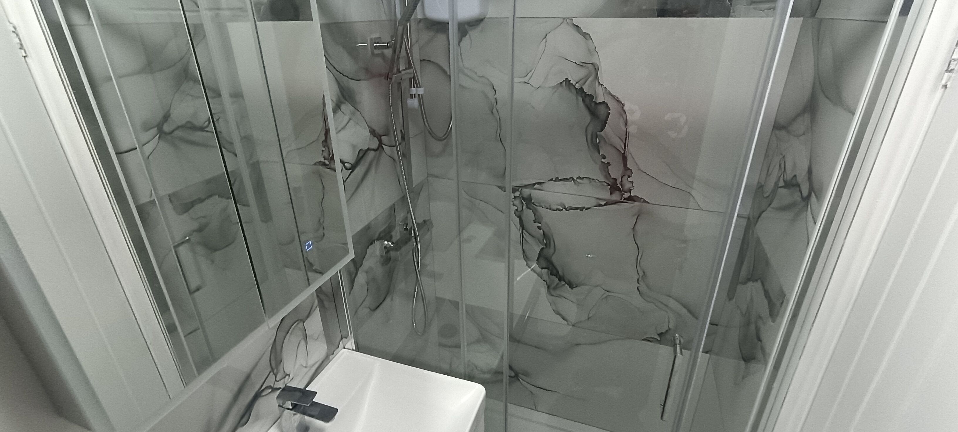 Baño con cabina de ducha de vidrio y lavabo blanco.