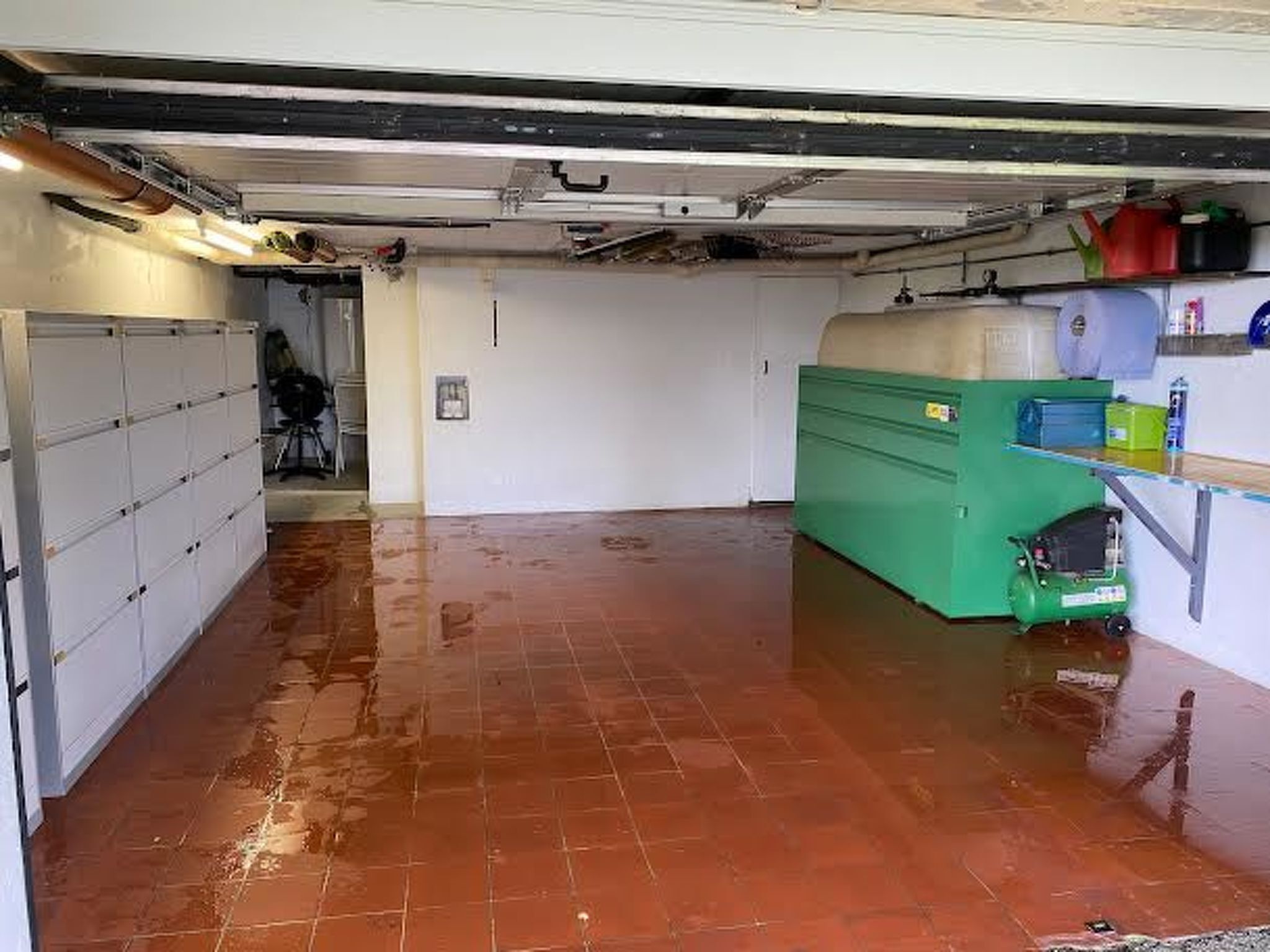 A wet basement with a green machine, a white door, and a metal staircase.