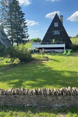 A triangular house with a stone wall in the foreground.