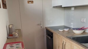 Eine kleine Küche mit einer weißen Tür, einer Holz Arbeitsplatte und einem Fliesenboden.
