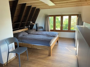 Una camera da letto con un letto di legno, una sedia, una scrivania e una finestra con tende.