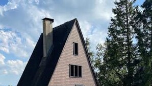 Ein dreieckiges Gebäude mit Schornstein, überdachtem Gang und Picknicktisch.