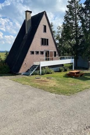 A house with a steeply pitched roof, a chimney, and a small porch with steps leading up to it.