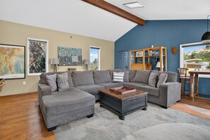 A living room with a sectional sofa, a coffee table, and a bookshelf. - New Listing! Vista Bonita | Private 10 Acres | Mountain Views | Shuffleboard (Santa Fe)