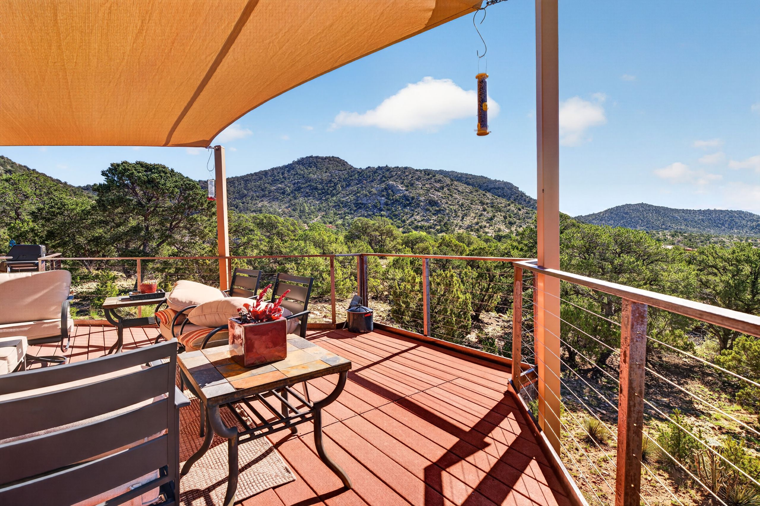 An outdoor deck with seating, a table, and a view of a mountainous landscape.