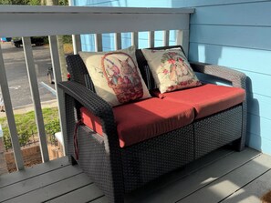 A wicker sofa with red cushions and floral pillows on a wooden deck. - Close Disney! Spacious 3Br 2 Bh Condo / 75" TV, Pool, Parking & No I-4 Traffic! (Kissimmee)