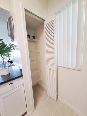A walk-in closet with open shelves and a mirrored closet door. - Close Disney! Spacious 3Br 2 Bh Condo / 75" TV, Pool, Parking & No I-4 Traffic! (Kissimmee)