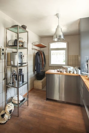 Cocina compacta con una isla central, una lámpara colgante y un ventanal.