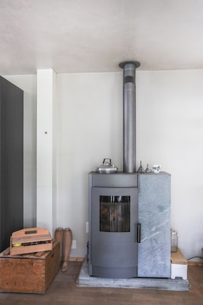 Een moderne houtkachel met schoorsteen, glazen deur en marmeren accent.