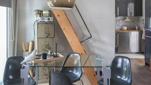 Eine moderne Küche mit einem Glastisch, schwarzen Stühlen und einer Holzbalkendecke.