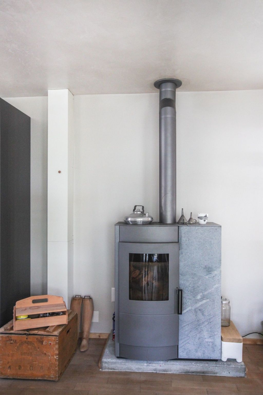 A modern wood-burning stove with a glass door, a chimney, and a marble accent.