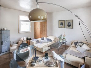 Una sala moderna con una mesa de centro de vidrio, un sofá, una cama con cabecera de madera y una lámpara de pie grande.