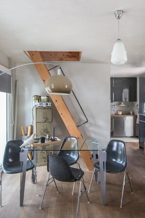 Una cocina moderna con una mesa de comedor de vidrio, sillas negras y vigas de madera.