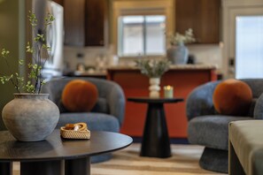 A modern living room with a round table, two armchairs, and a vase with green plants. - Gem State Getaway  Game Room+Arcades+Poker+BBQ (Boise)