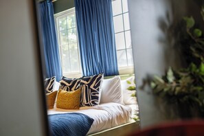 Un dormitorio con una cama, cortinas azules y una ventana.