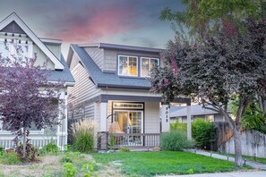 A two-story residential house with a visible front porch, a swing chair, and a well-maintained lawn. - Gem State Getaway  Game Room+Arcades+Poker+BBQ (Boise)
